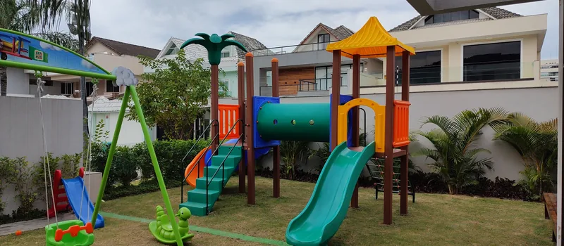 Área de lazer com grama sintética e brinquedos em condomínio